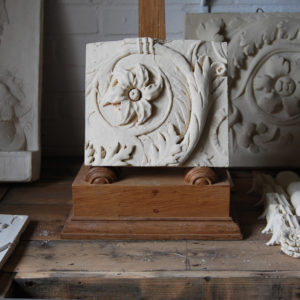 A cast plaster relief of a flowerhead and frond leaf scroll-0
