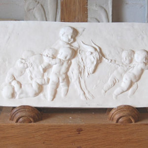 An English relief cast plaster plaque of Putti with a goat-0