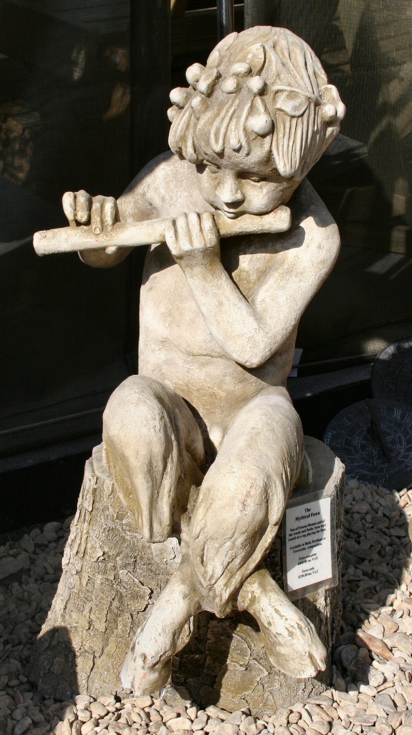 A composition stone Faun seated on a log-0