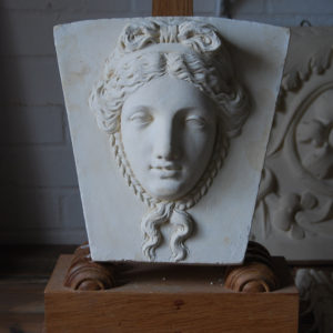 A cast plaster keystone with a classical head of a maiden-0