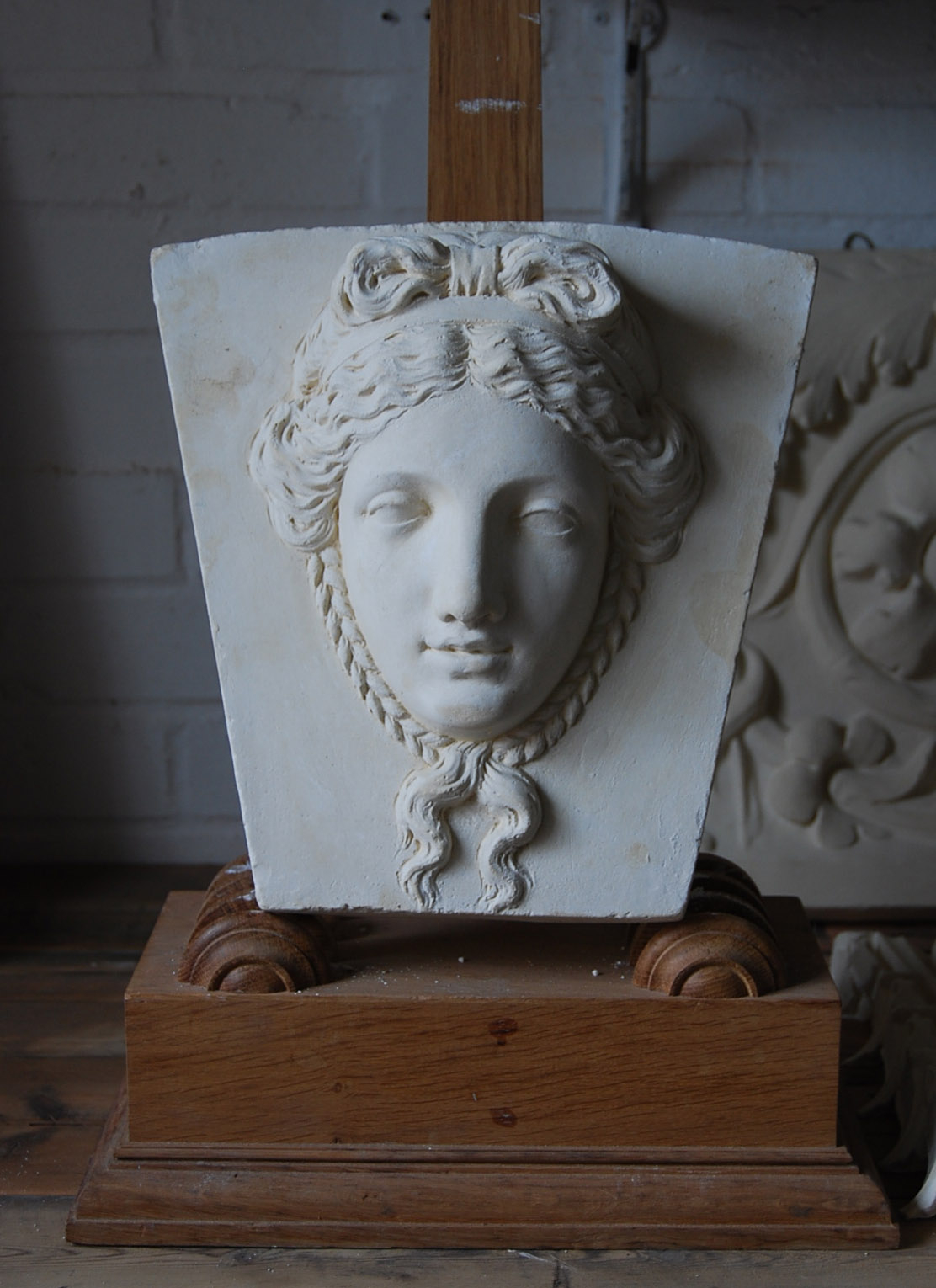 A cast plaster keystone with a classical head of a maiden-0