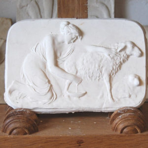 An English relief cast plaster plaque of a Shepherdess milking an ewe-0