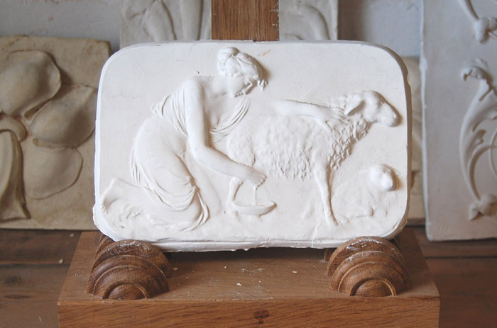 An English relief cast plaster plaque of a Shepherdess milking an ewe-0